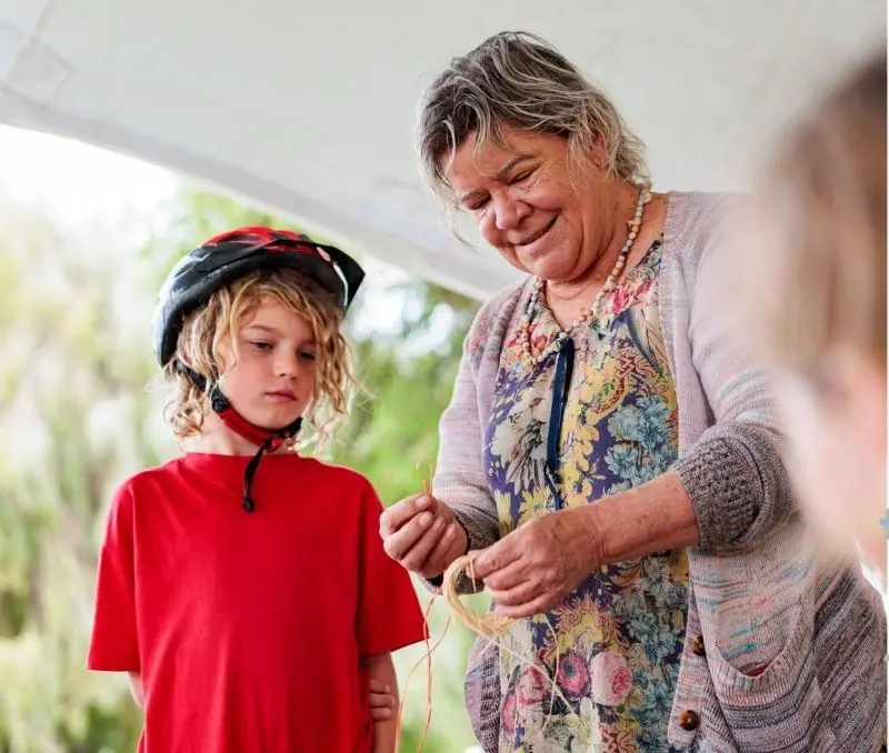 A boy being taught how to weave.