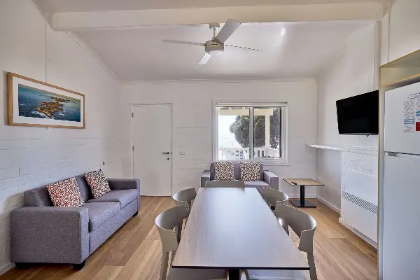 A dining table and chairs with a tv and two sofas in the room.