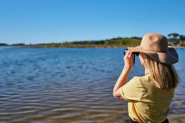 Stylish Girl Bird Watching with binoculars over the salt lakes on Wadjemup / Rottnest Island