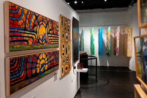 A selection of beautiful Aboriginal artworks from the Connections to Wadjemup exhibition on white textured walls.