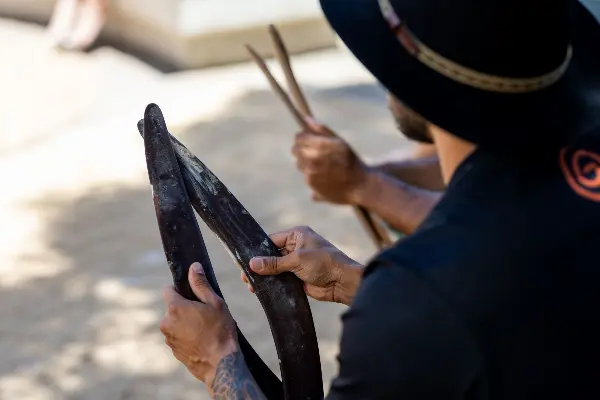 A man holding two boomerangs.