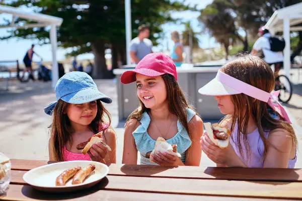 Three girls enjoying a picnic from the barbeques at The Basin.