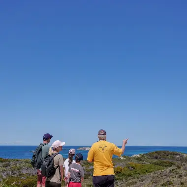 A Volunteer from the Rottnest Island Volunteer Guides showing a family the coastline on Rottnest Island