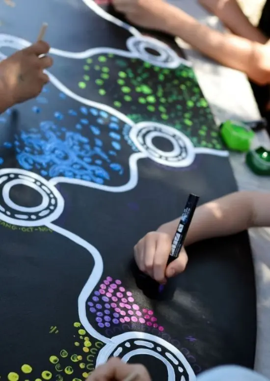 Kids drawing on a surfboard during Koorda's crew drawing workshop.