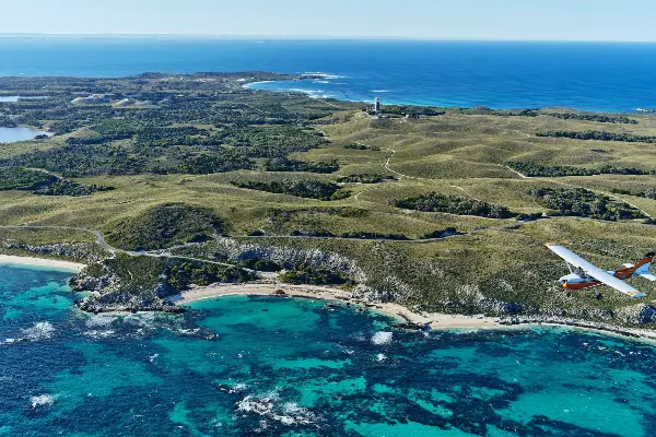 Rottnest Air-Taxi flying over the luscious green hills of Rottnest Island.