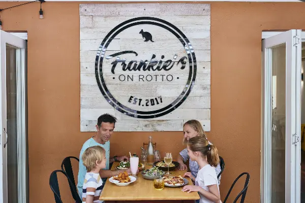 Family enjoying food outside underneath the Frankie's on Rotto sign