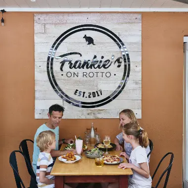 Family enjoying food outside underneath the Frankie's on Rotto sign