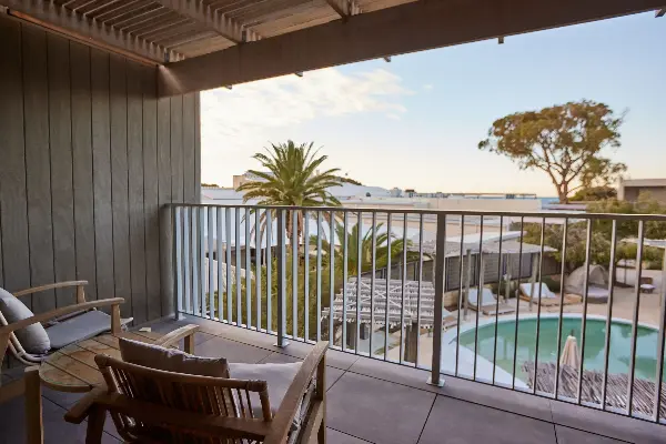 Two chairs and a table on a balcony overlooking the pool.