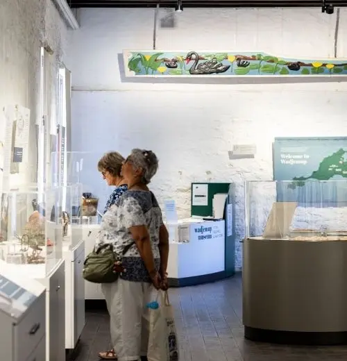 Two people looking at artworks in Wadjemup Museum.